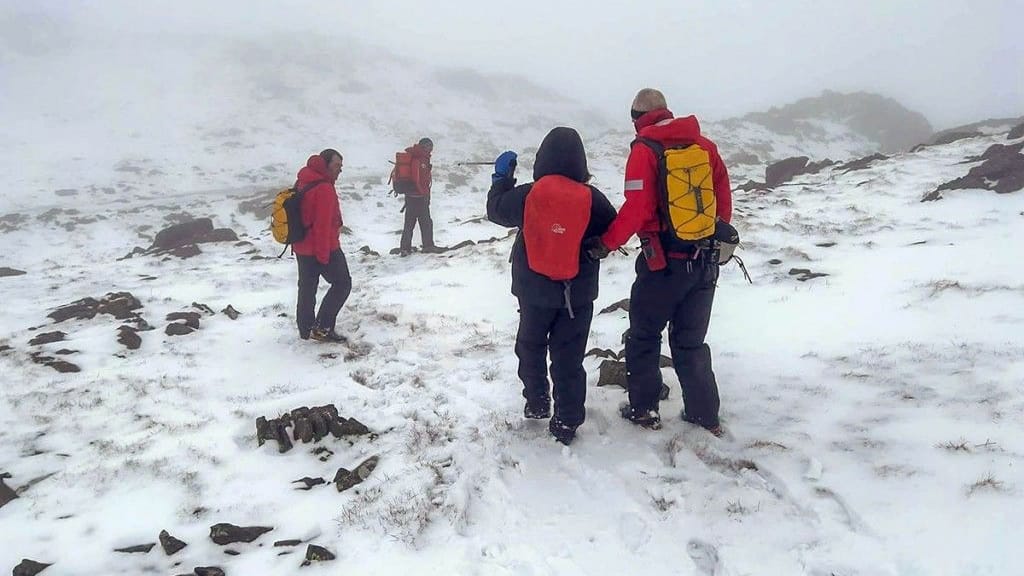 mountain rescue teams helping an injured woman as winter conditions return to the lakeland falls