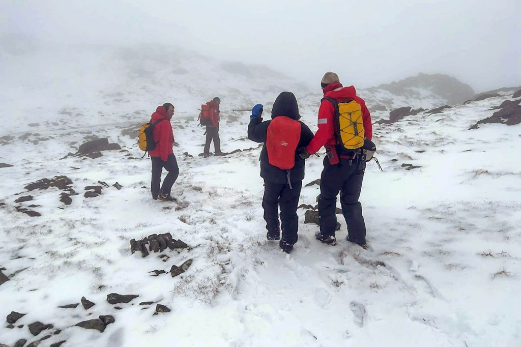 mountain rescue teams helping an injured woman as winter conditions return to the lakeland falls