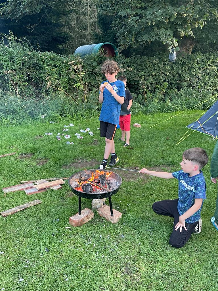 Corey eating a s'moores and Carter warming a marshmallow over a fire